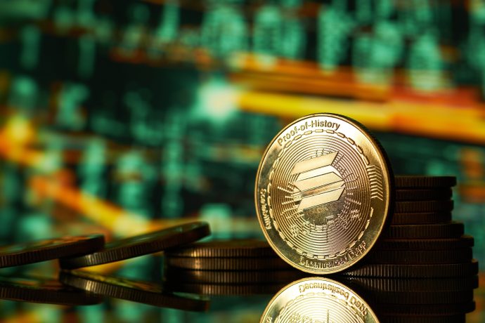 Eine goldene Solana-Kryptowährungsmünze steht aufrecht auf einem Münzstapel, mit einem unscharfen Hintergrund aus digitalen Solana-Finanzdaten.