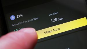 Ein Finger berührt ein Smartphone-Display, auf dem eine Option für ETH-Einsätze über 120 Tage angezeigt wird, wobei die Schaltfläche "Stake Now" (Jetzt einsetzen) hervorgehoben und der annualisierte Zinssatz angezeigt wird.