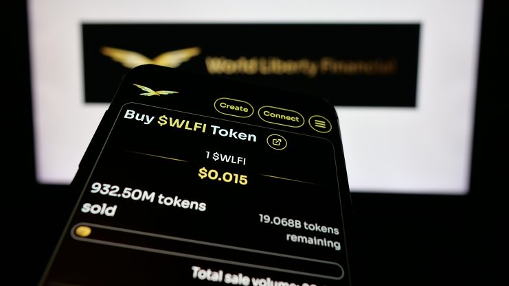 Ein Smartphone-Bildschirm zeigt die Option zum Kauf von WLFI-Token zu je $0,015 an. Es werden 932,50 Millionen Token verkauft und 19,07 Millionen WLFI-Token verbleiben. Im Hintergrund ist das World Liberty Financial-Logo zu sehen.