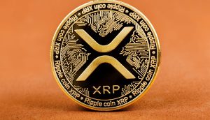 Physische goldene XRP-Münze vor orangefarbenen Hintergrund
