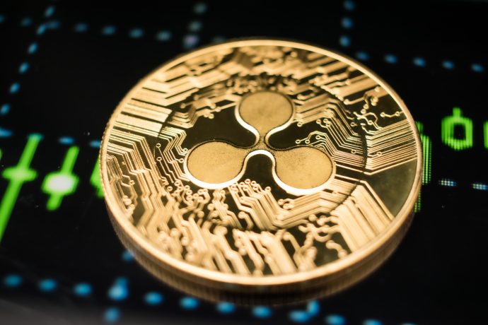 Eine goldene XRP-Kryptowährungsmünze wird auf einem digitalen Finanzchart-Hintergrund platziert.
