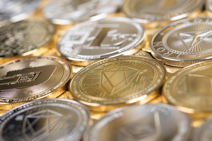 Eine Nahaufnahme verschiedener Krypto-Münzen, darunter Bitcoin, Ethereum und Litecoin, die in überlappenden Reihen angeordnet sind.