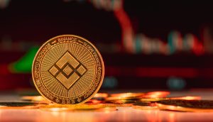 Zu sehen ist ein BNB Coin vor einem Krypto-Chart