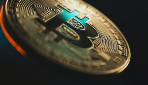 Nahaufnahme einer physischen Bitcoin-Münze mit detaillierten Schaltkreismustern und dem ikonischen Bitcoin-Symbol vor einem dunklen, verschwommenen Hintergrund. Bitcoin Kurs Korrektur nach Allzeithoch und Jackson Hole Symposium Auswirkung auf Bitcoin Chart