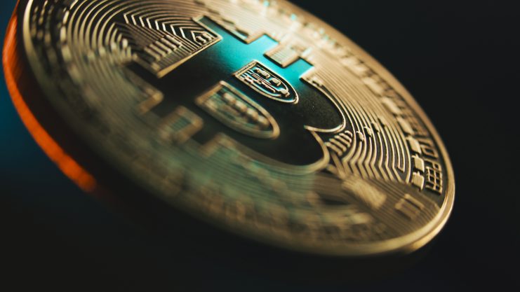 Nahaufnahme einer physischen Bitcoin-Münze mit detaillierten Schaltkreismustern und dem ikonischen Bitcoin-Symbol vor einem dunklen, verschwommenen Hintergrund. Bitcoin Kurs Korrektur nach Allzeithoch und Jackson Hole Symposium Auswirkung auf Bitcoin Chart
