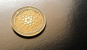 Eine goldfarbene Cardano ADA-Kryptowährungsmünze ruht auf einer strukturierten dunklen Oberfläche, die die Eleganz von Cardano unterstreicht.