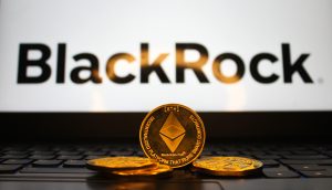 Drei Ethereum-Münzen liegen auf einer Laptop-Tastatur, während im Hintergrund das BlackRock-Logo auf dem Bildschirm angezeigt wird.