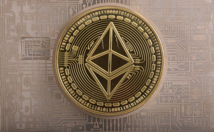 Eine goldene Ethereum-Münze mit dem Ethereum-Symbol ist auf einem Platinenhintergrund platziert und steht für die Kryptowährung Ethereum und die Blockchain-Technologie.