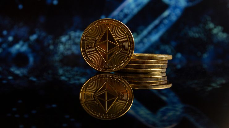 Ein Stapel goldfarbener Ethereum-Reserve-Münzen wird vor einem dunklen, abstrakten Hintergrund mit blauen Kettengrafiken angezeigt, wobei die Münzen darunter reflektiert werden.
