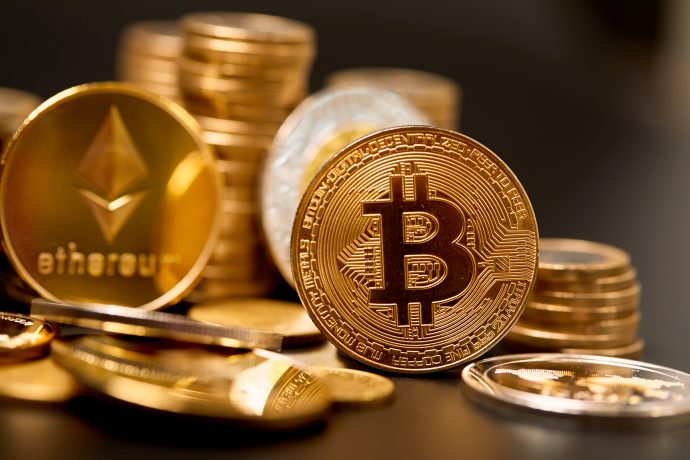 Nahaufnahme von physischen Münzen, die Kryptowährungen, einschließlich Bitcoin und Ethereum, repräsentieren und in einem Stapel auf einer dunklen Oberfläche angeordnet sind - ein Symbol für die jüngste Stabilisierung des Krypto-Marktes.