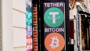 Ein Schild vor einem Gebäude zeigt die Logos und Namen beliebter Kryptowährungen, darunter Tether und Bitcoin.