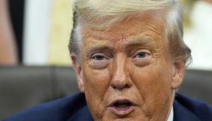 Nahaufnahme von Donald Trump mit hellem Haar und Anzug, der in einem Haus sitzt und leicht zur Seite blickt, wobei sein Mund teilweise geöffnet ist - vielleicht bespricht er einen aktuellen Rekord der Trump Media Group.