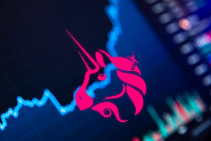 Das rosafarbene Uniswap-Einhorn-Logo hebt sich von einem verschwommenen Kryptowährungspreisdiagramm ab.