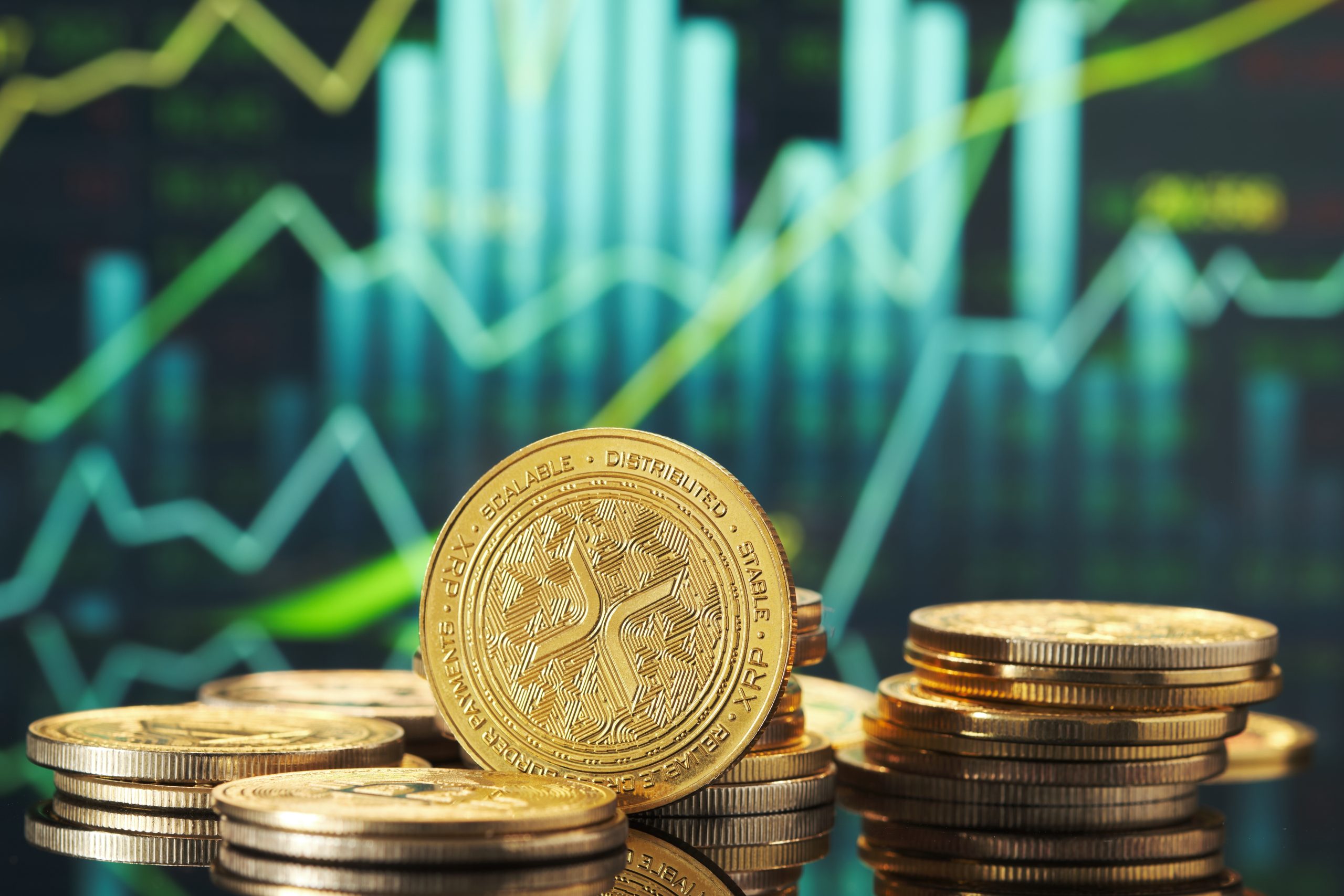 Im Mittelpunkt stehen Stapel goldfarbener Kryptowährungsmünzen, darunter XRP, mit einem digitalen Finanzdiagramm, das im unscharfen Hintergrund steigende Graphen anzeigt.