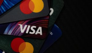 Nahaufnahme von sich überlappenden Kredit- und Debitkarten, einschließlich Visa und Mastercard, vor einem dunklen Hintergrund - ein Hinweis auf die sich entwickelnde Verbindung zwischen dem traditionellen Finanzwesen und Stablecoins.