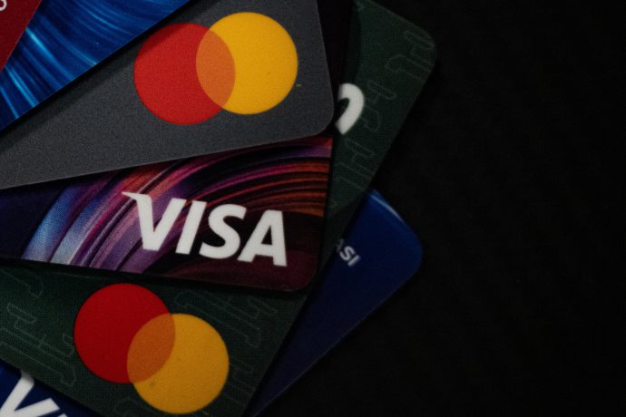 Nahaufnahme von sich überlappenden Kredit- und Debitkarten, einschließlich Visa und Mastercard, vor einem dunklen Hintergrund - ein Hinweis auf die sich entwickelnde Verbindung zwischen dem traditionellen Finanzwesen und Stablecoins.