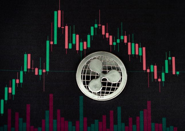 Eine Ripple-Münze (XRP) auf einem digitalen Bildschirm, der ein Candlestick-Diagramm mit roten und grünen Balken anzeigt, das die Handelsdaten von Kryptowährungen und das wachsende Interesse an Spot-ETFs darstellt.