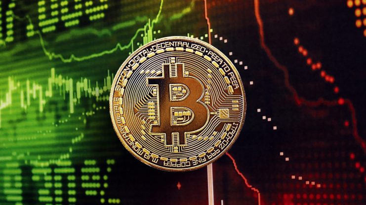 Ein physischer Bitcoin-Token wird vor einem digitalen Bildschirm gezeigt, der fluktuierende grüne und rote Bitcoin-Finanzcharts anzeigt.