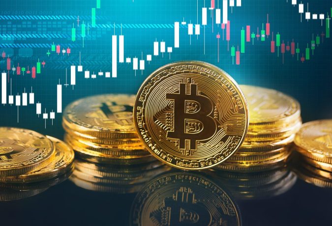 Stapel von goldfarbenen Bitcoin-Token mit einem digitalen Preisdiagramm im Hintergrund, das eine aktuelle BTC-Kursrallye hervorhebt.