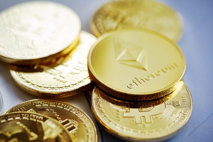 Eine Nahaufnahme von mehreren goldfarbenen Kryptowährungsmünzen, darunter Bitcoin und Ethereum - ein Blick in das Krypto-Universum mit einigen der widerstandsfähigsten Münzen, gestapelt und überlappend auf einer glatten Oberfläche.