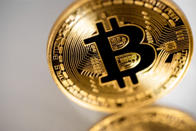 Eine Nahaufnahme einer physischen Bitcoin-Münze mit dem Bitcoin-Symbol und kreislaufähnlichen Details, die die Kryptowährung auch auf einem Bärenmarkt repräsentieren.