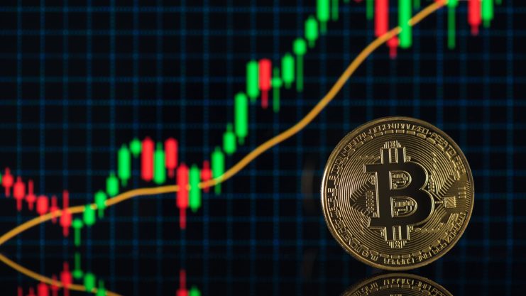 Eine goldene Bitcoin-Münze steht vor einem digitalen Bildschirm, der einen Candlestick-Chart mit steigenden grünen und roten Kurstrends anzeigt, der den aktuellen BTC-Kurs widerspiegelt und die neueste Bitcoin-Prognose eines Experten unterstützt.