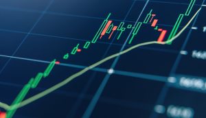 Eine Nahaufnahme eines digitalen Finanzcharts zeigt grüne und rote Kerzen mit einer gelben Trendlinie auf dunklem Hintergrund, die auf ein neues Allzeithoch hinweist.