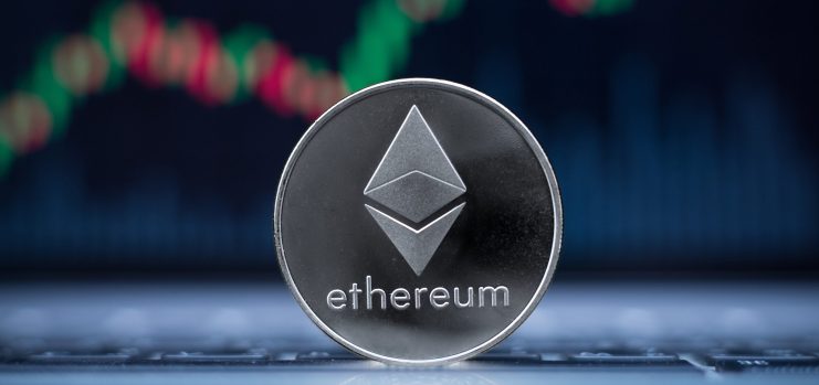 Eine silberne Ethereum-Münze (ETH) steht aufrecht auf einer Fläche mit einem unscharfen Finanzchart mit grünen und roten Kerzen im Hintergrund, was darauf hindeutet, dass ETH sich der 4.000 US-Dollar-Marke nähert.