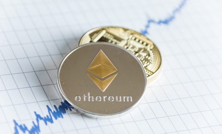 Eine silberne Ethereum-Münze und eine goldene Bitcoin-Münze sind auf einem Papier mit einem blauen, aufwärts gerichteten Liniendiagramm platziert, das den jüngsten ETF-Rekordzufluss auf den Kryptowährungsmärkten symbolisiert.