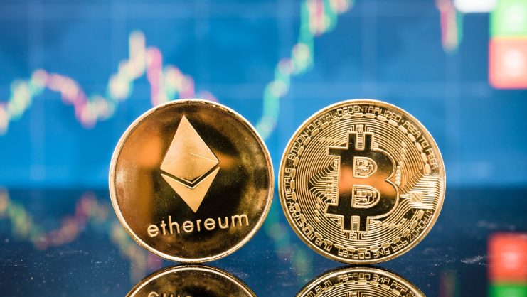 Physische Münzen, die Ethereum und Bitcoin repräsentieren, werden vor einem unscharfen Bildschirm mit Marktdaten angezeigt, der die dynamische Welt einfängt, die in jedem Krypto-Report verfolgt wird.