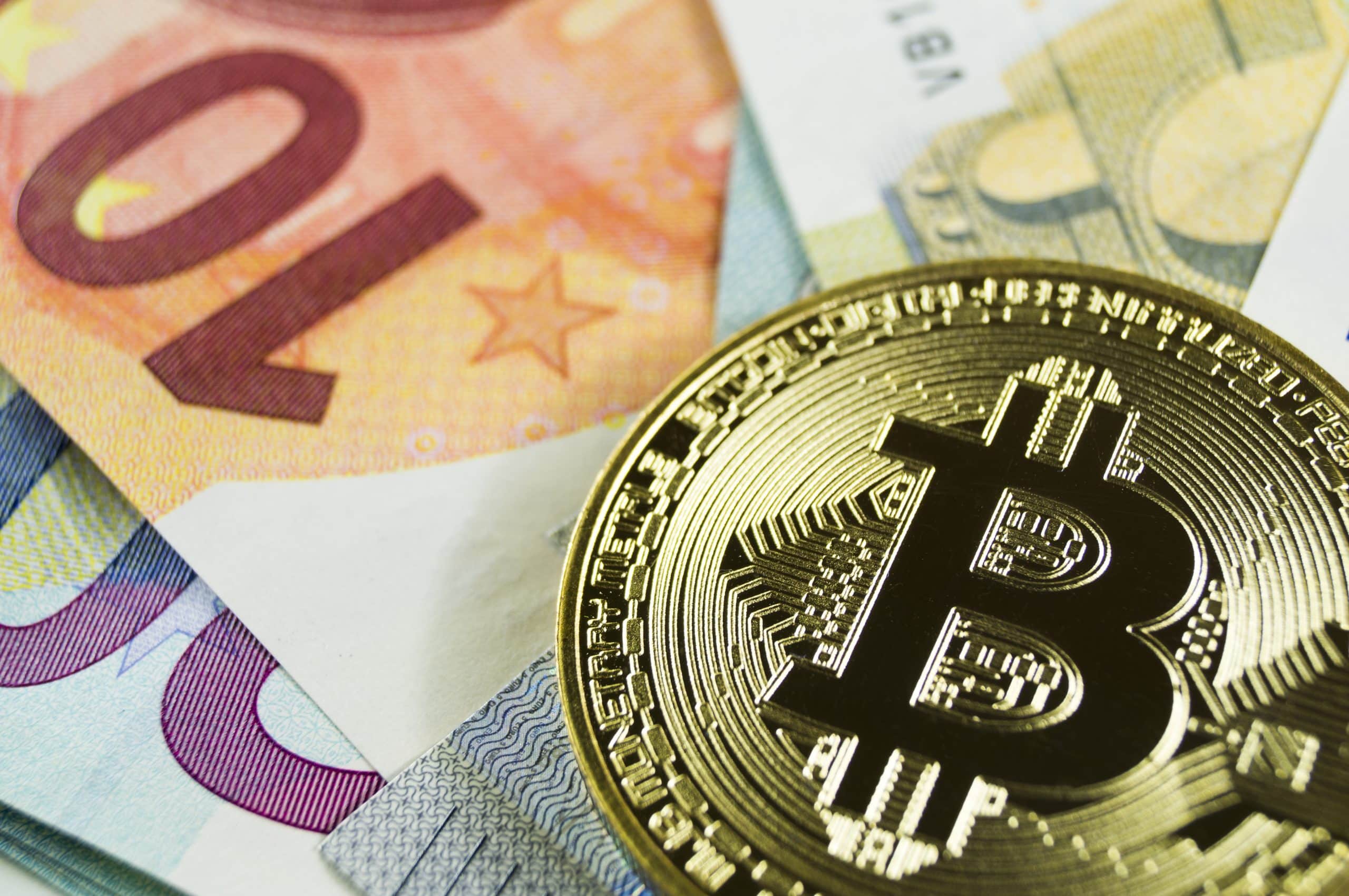 Eine goldene Bitcoin-Münze auf verschiedenen Euro-Banknoten, darunter 10- und 20-Euro-Scheine, verdeutlicht den wachsenden Einfluss von Kryptowährungen in der heutigen Finanzlandschaft.