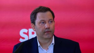 Lars Klingbeil, Vorsitzender der SPD, spricht bei einer Krypto-Veranstaltung vor einem roten Hintergrund mit SPD-Logo.