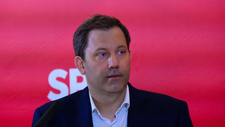 Lars Klingbeil, Vorsitzender der SPD, spricht bei einer Krypto-Veranstaltung vor einem roten Hintergrund mit SPD-Logo.