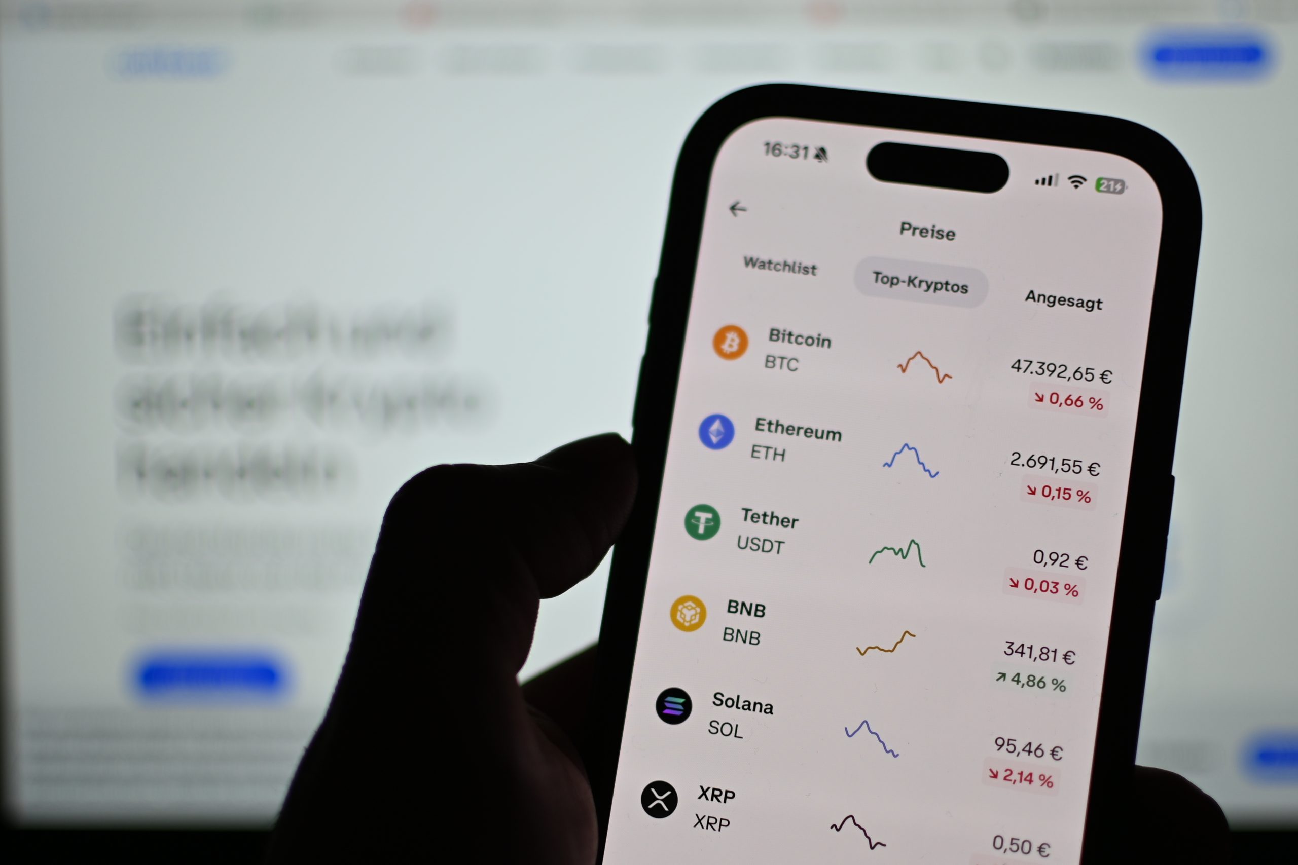 Eine Person hält ein Smartphone, auf dem Krypto-Kurse und Charts für Bitcoin, Ethereum, Tether, BNB, Solana und XRP angezeigt werden - alles in deutscher Sprache.