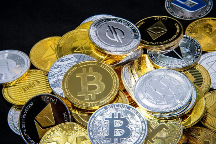 Ein Stapel verschiedener physischer Münzen, darunter Bitcoin, Ethereum und Litecoin, die verschiedene Kryptowährungen auf einem schwarzen Hintergrund repräsentieren.