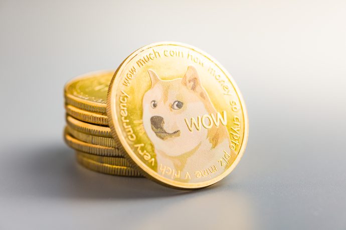 Ein Stapel goldener Dogecoin-Münzen mit dem Dogecoin-Logo, einem Shiba Inu-Hund und dem Wort WOW auf der Vorderseite der Münze.