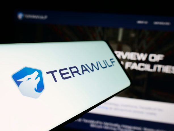 Ein Smartphone-Bildschirm zeigt das TeraWulf-Logo und den Namen, im Hintergrund ist eine unscharfe TeraWulf-Website mit Bitcoin-Thema zu sehen.