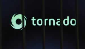 Ein unscharfes Bild mit dem Schriftzug Tornado Cash und einem wirbelnden Logo, das teilweise von dunklen vertikalen Balken im Vordergrund verdeckt wird.