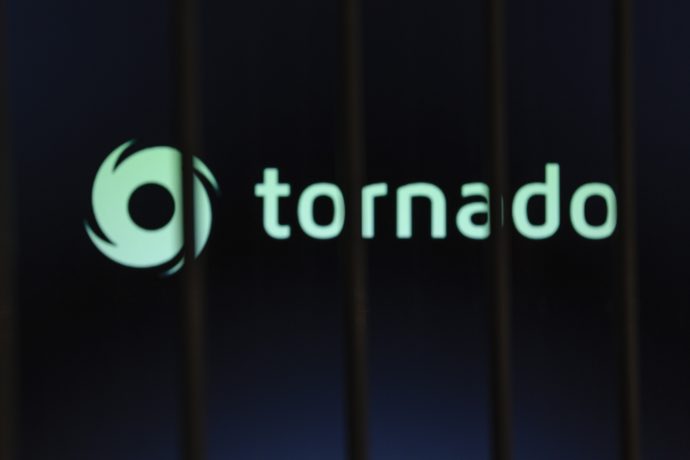 Ein unscharfes Bild mit dem Schriftzug Tornado Cash und einem wirbelnden Logo, das teilweise von dunklen vertikalen Balken im Vordergrund verdeckt wird.