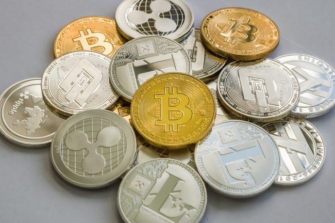 Ein Stapel verschiedener Kryptowährungsmünzen mit goldenen und silbernen Darstellungen von Bitcoin, Litecoin und Ripple, die auf einem einfachen Hintergrund angezeigt werden.
