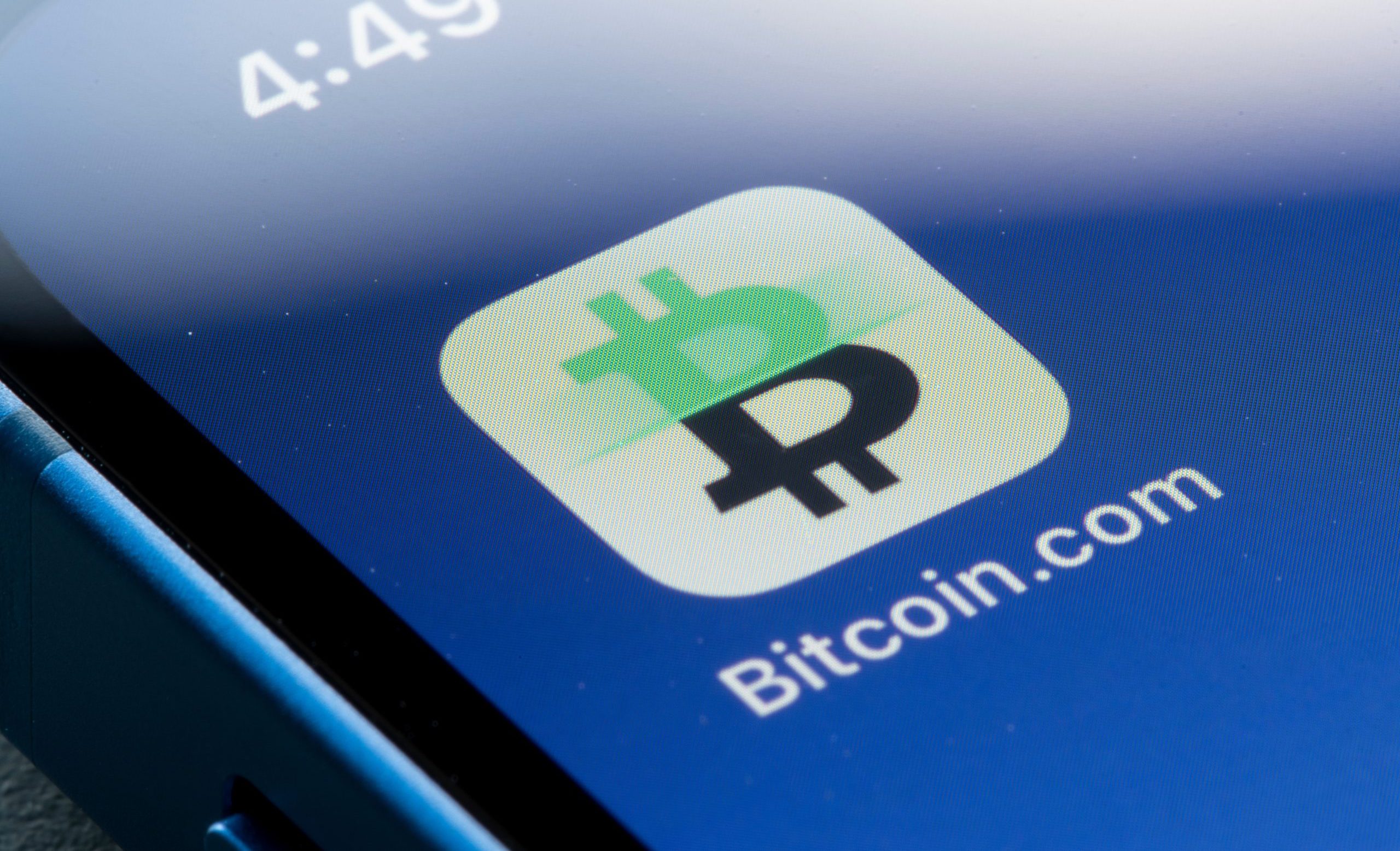 Nahaufnahme eines Smartphone-Bildschirms, auf dem das Bitcoin.com-App-Symbol angezeigt wird, wobei der Name Bitcoin neben der Uhrzeit 4:49 in der linken oberen Ecke hervorgehoben wird.