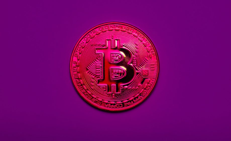 Symbolische Darstellung einer roten Bitcoin-Münze auf lila Hintergrund – Hinweis auf eine potenzielle 51-Prozent-Attacke im Bitcoin-Netzwerk.