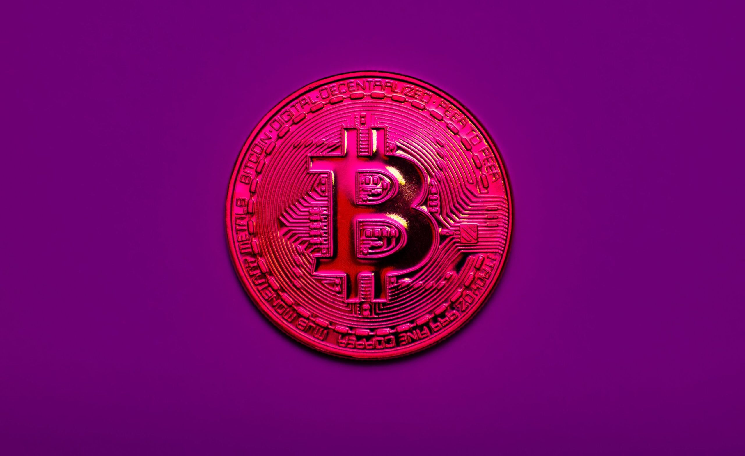 Symbolische Darstellung einer roten Bitcoin-Münze auf lila Hintergrund – Hinweis auf eine potenzielle 51-Prozent-Attacke im Bitcoin-Netzwerk.