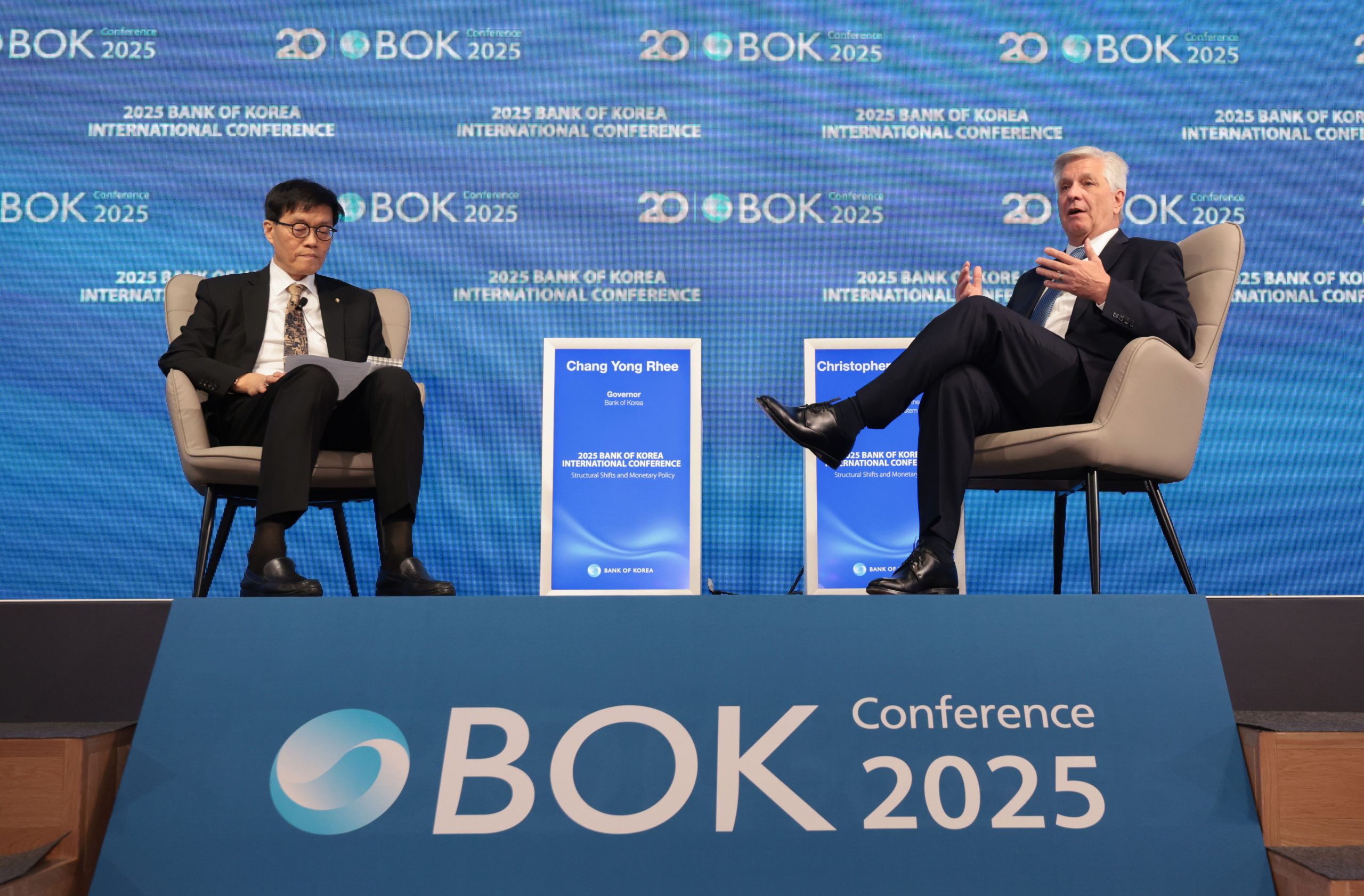 Zwei Männer sitzen auf der BOK Conference 2025 auf einer Bühne, zwischen ihnen ist das Event-Branding und eine Anzeige mit der Aufschrift Chang Yong Rhee zu sehen, und diskutieren über DeFi und die Auswirkungen auf die traditionellen Rollen von Bankern.