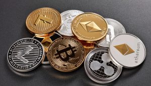 Ein Stapel verschiedener physischer Kryptowährungsmünzen, darunter Bitcoin, Ethereum, Litecoin und Ripple, angeordnet auf einer dunklen Oberfläche. Die herausragende Bitcoin-Münze sticht aus dieser beeindruckenden Sammlung hervor.