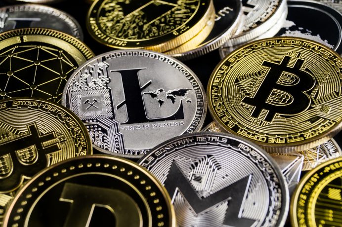 Eine Nahaufnahme verschiedener physischer Kryptowährungsmünzen, darunter bekannte Bitcoin-Token sowie Litecoin, Dogecoin und Monero, die aufeinander gestapelt sind und sich überlappen.