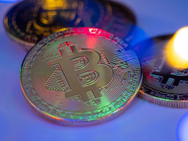 Nahaufnahme von physischen Bitcoin-Token mit farbiger, reflektierender Beleuchtung, die den Reiz von Krypto-Assets hervorhebt.