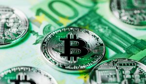 Die silbernen Bitcoin-Münzen sind auf einem grünen 100-Euro-Schein platziert und symbolisieren die Beziehung zwischen Kryptowährung und traditionellem Geld - perfekt für alle, die sich fragen: "Soll ich 1.000 Euro in Bitcoin investieren?.