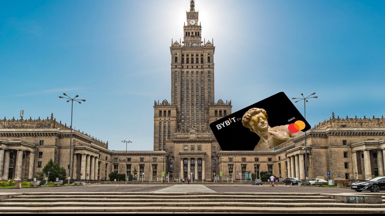 Eine große Bybit Card Mastercard-Kreditkarte mit einer Statue wird an einem sonnigen Tag vor dem Palast für Kultur und Wissenschaft in Warschau, Polen, digital hinzugefügt.