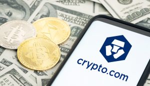 Drei Kryptowährungsmünzen und ein Smartphone mit dem Crypto.com-Logo sind auf mehreren US-Dollarnoten platziert, um die Verbindung zwischen digitalen Vermögenswerten und traditionellen Finanzen zu verdeutlichen, die Crypto.com herstellt.